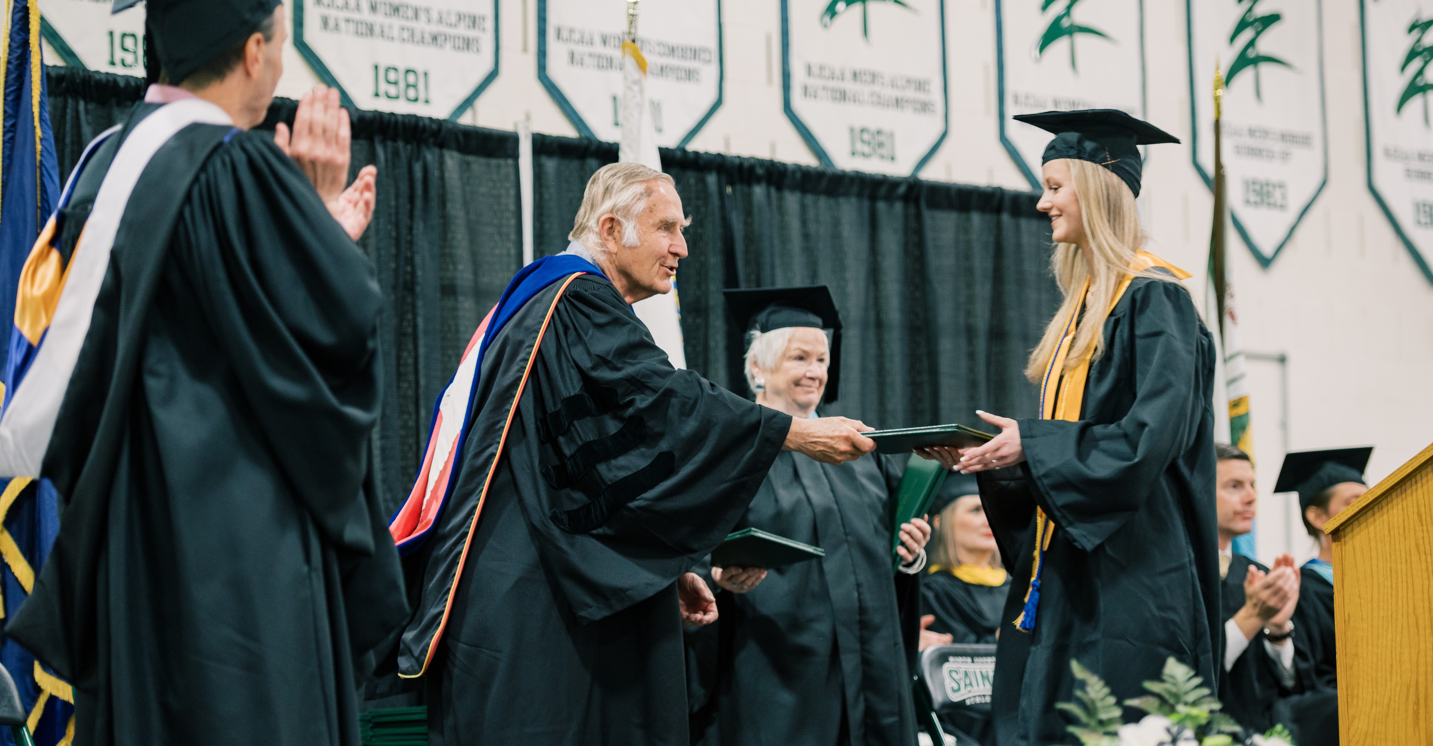 A student receives her diploma on stage during a college graduation ceremony