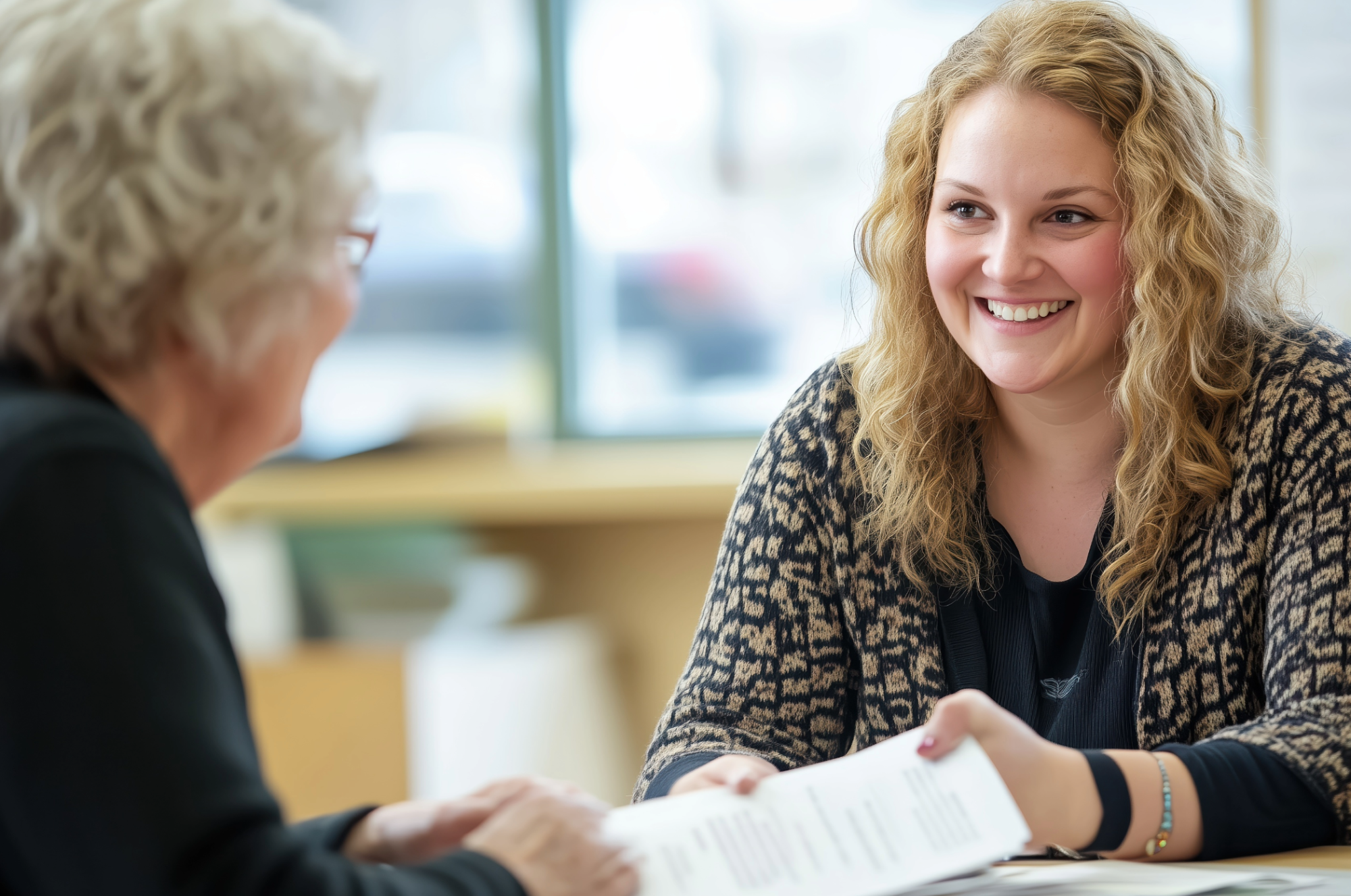 A woman listens to another woman as they sit at a table