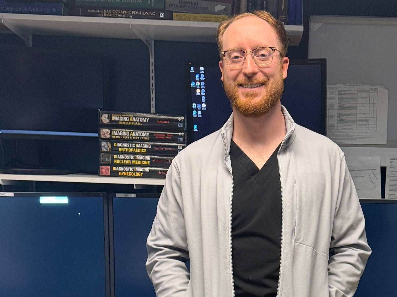 Tyler Belleau, Class of 2015, Radiologic Technology Tyler Belleau stands in a hospital room facing the camera and smiling