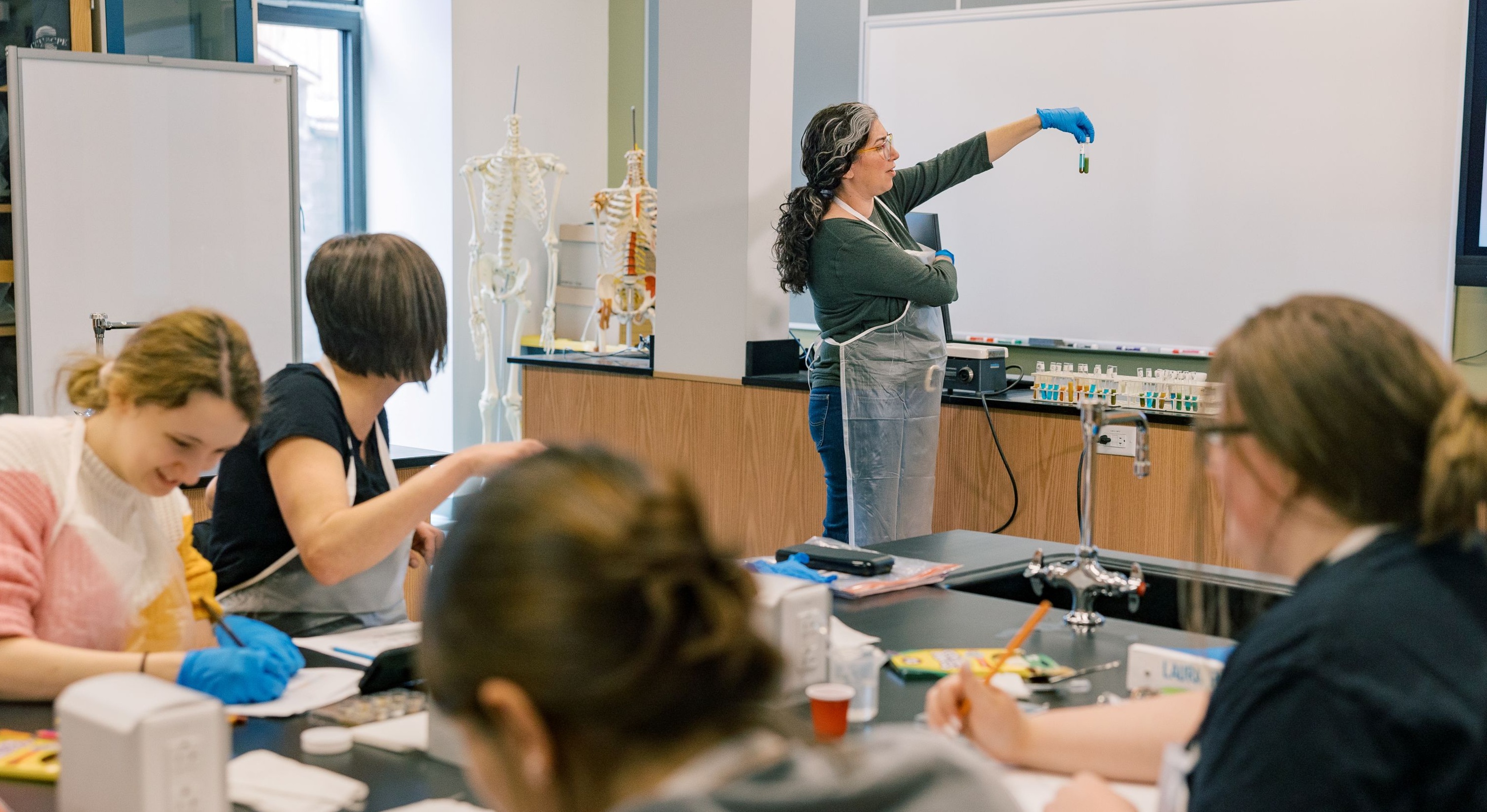 Students listen to an instructor in a science lab