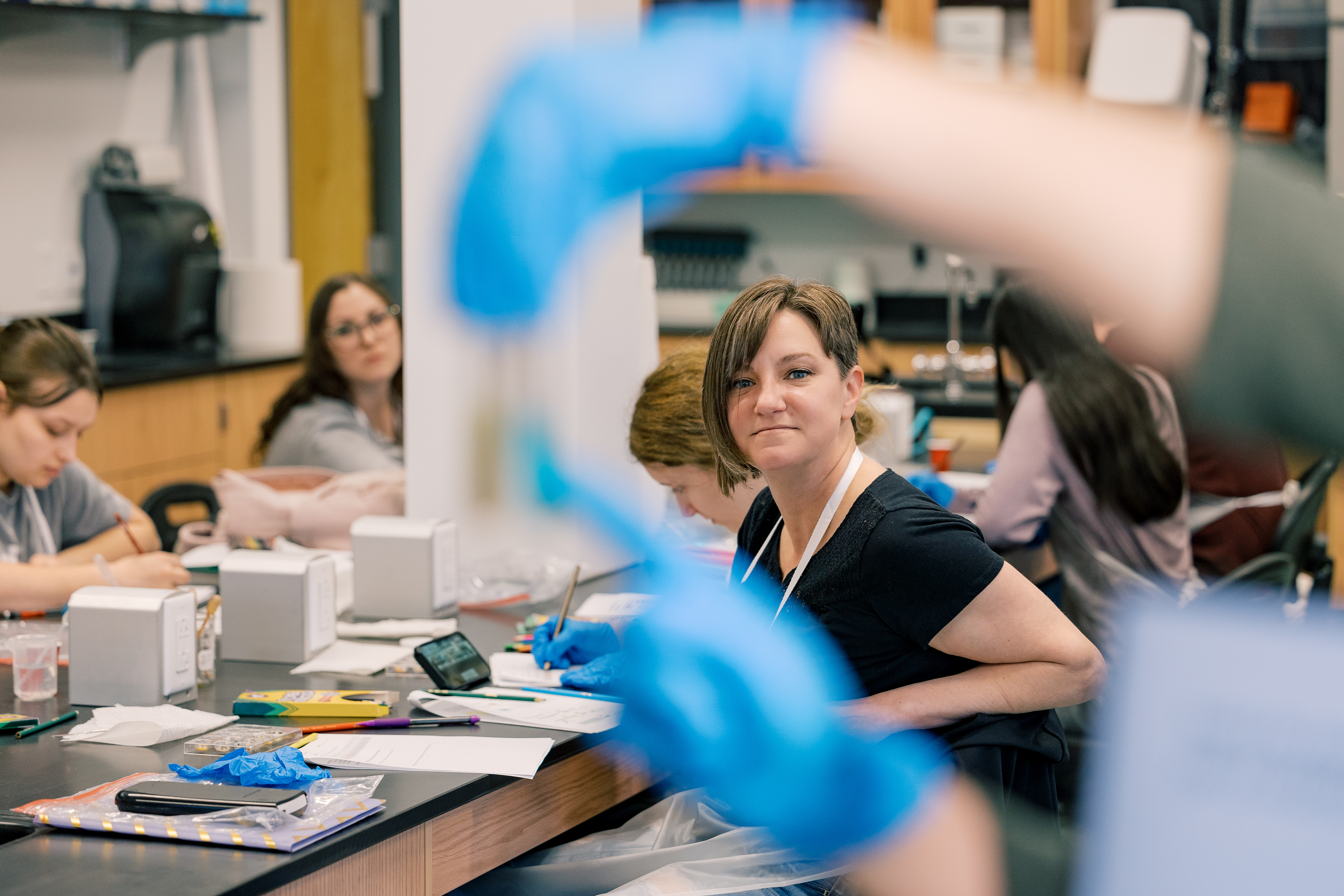 A student sits at a table in the college's nursing lab and smiles 