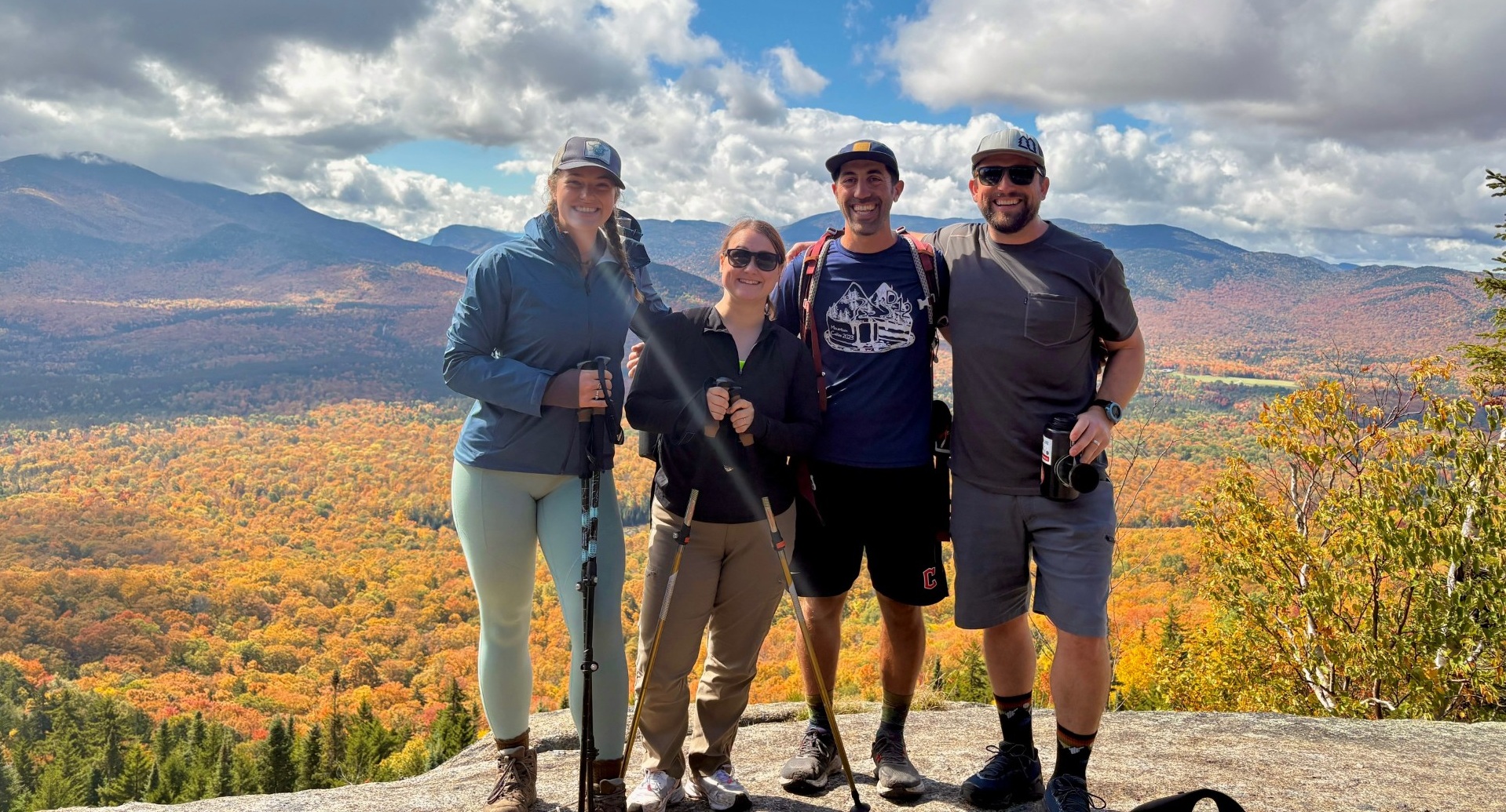 Students and instructors stand on a mountaintop with a backdrop of mountains in fall colors