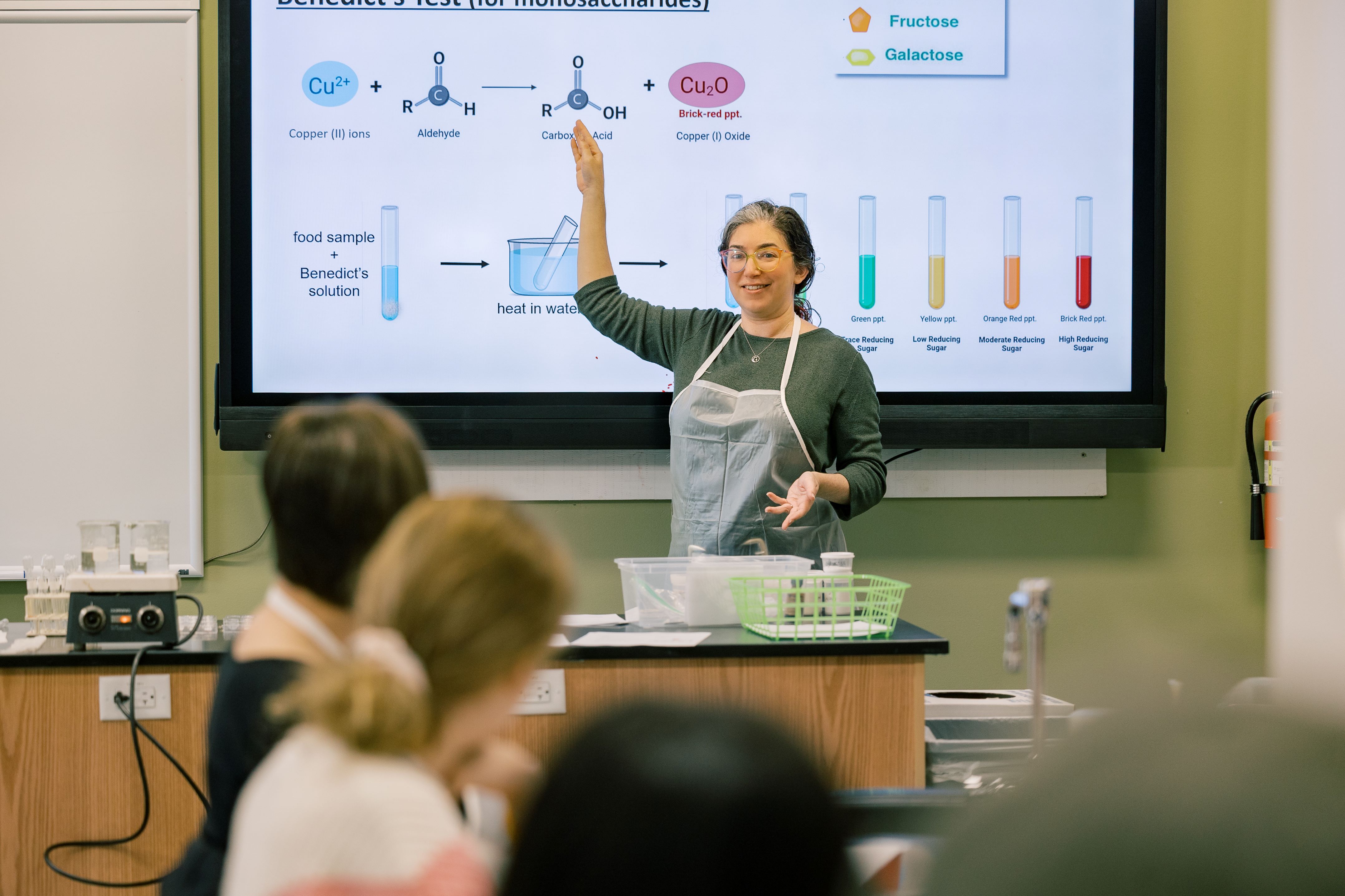 A college professor stands in front of a class in a science lab
