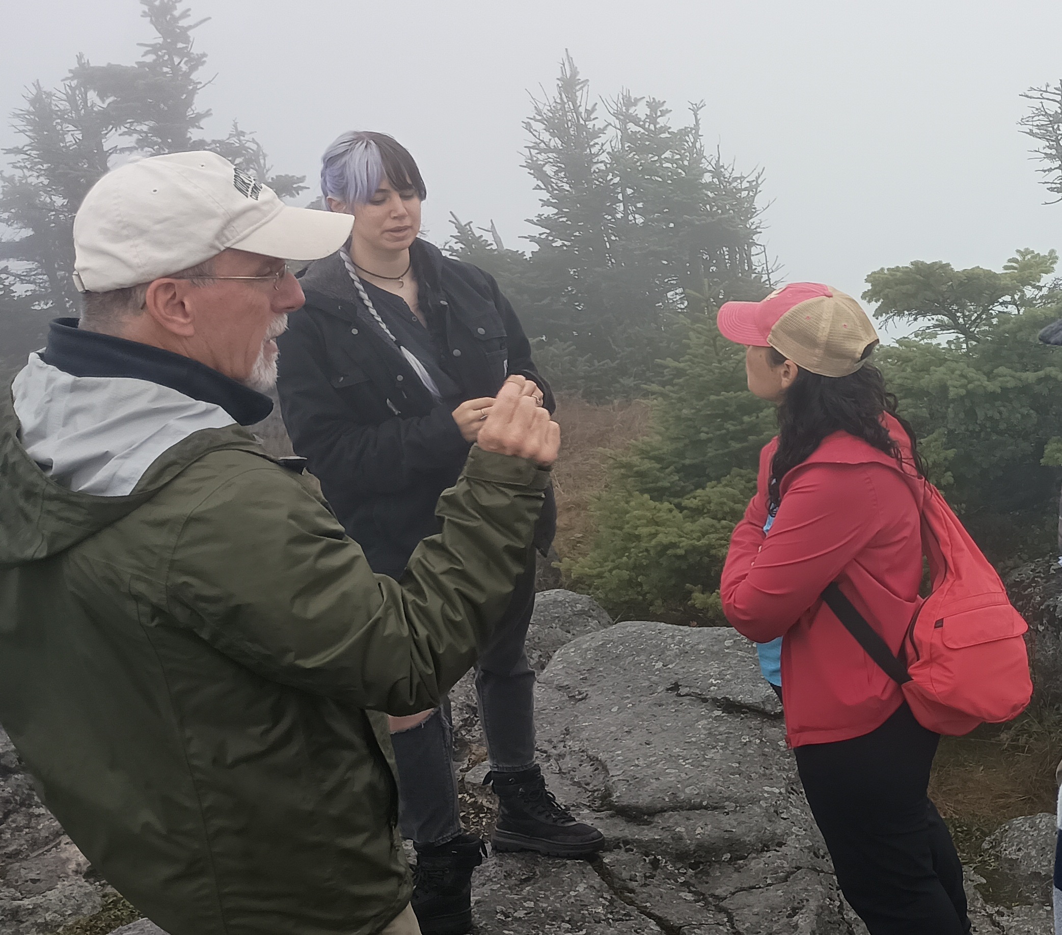 A science instructor speaks to a group of students on a mountain summit.