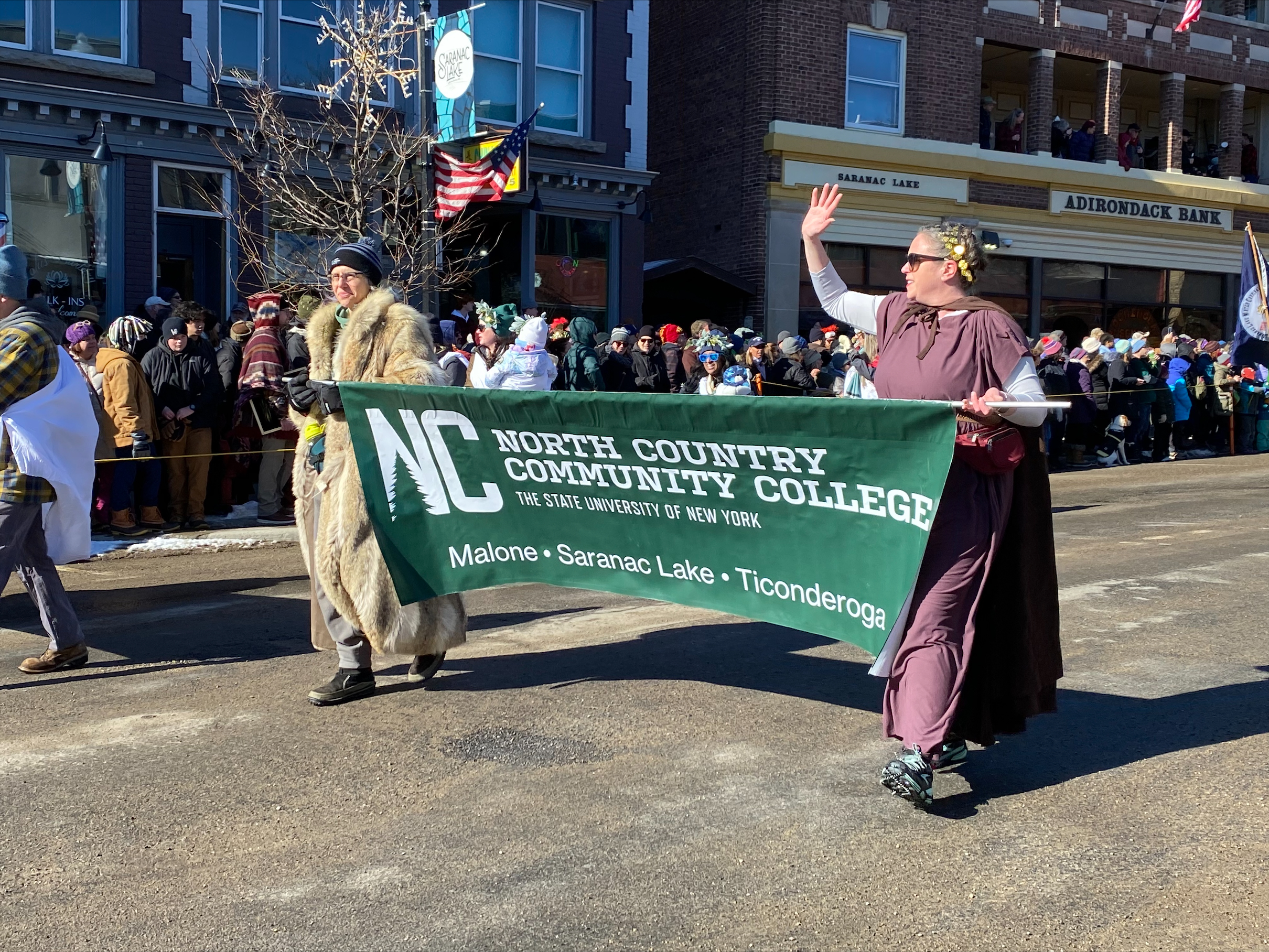 Shir Filler and Cait Keefe carry the NCCC banner during the Winter Carnival parade.