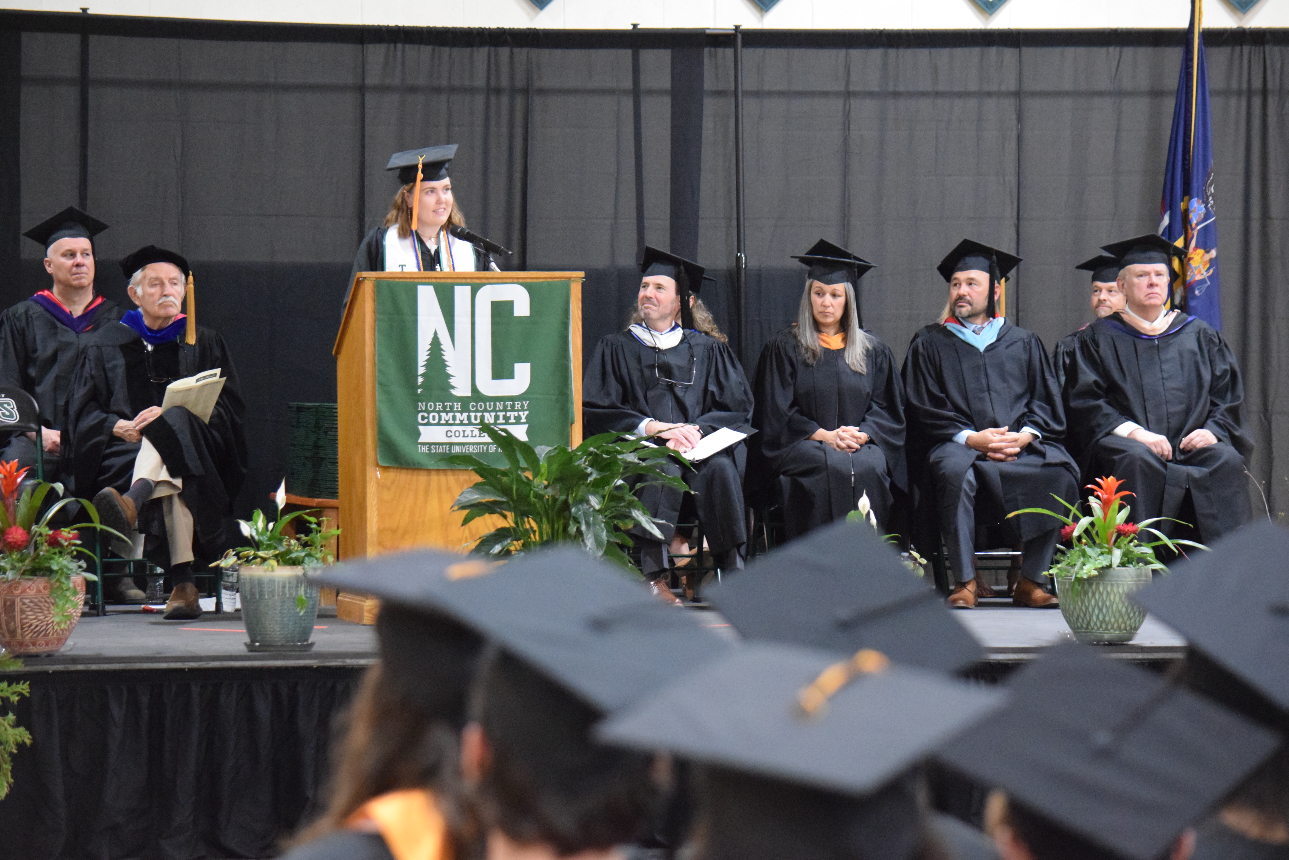 A speaker stands behind a podium during a college graduation ceremony