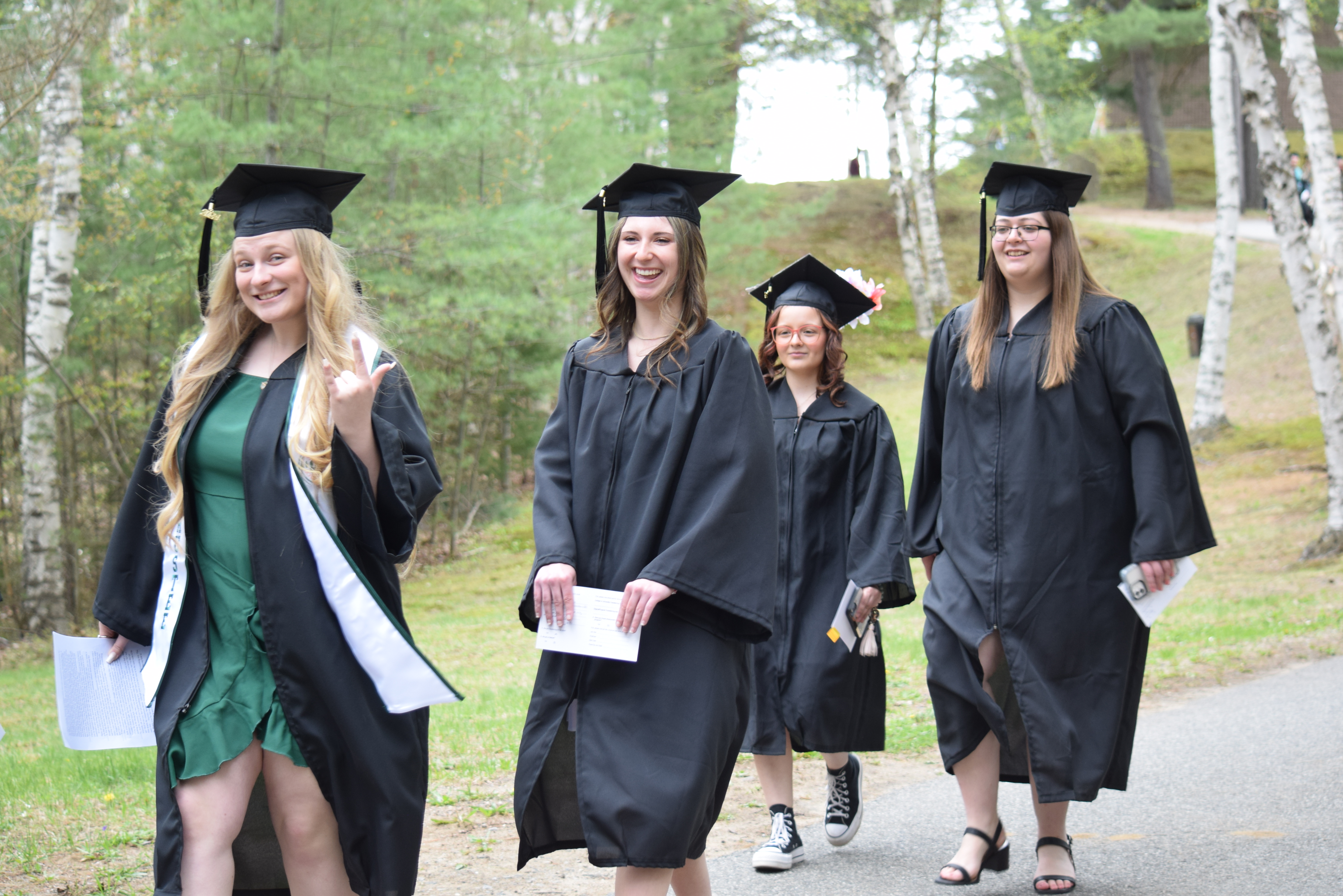 Students in graduation attire smile at the camera