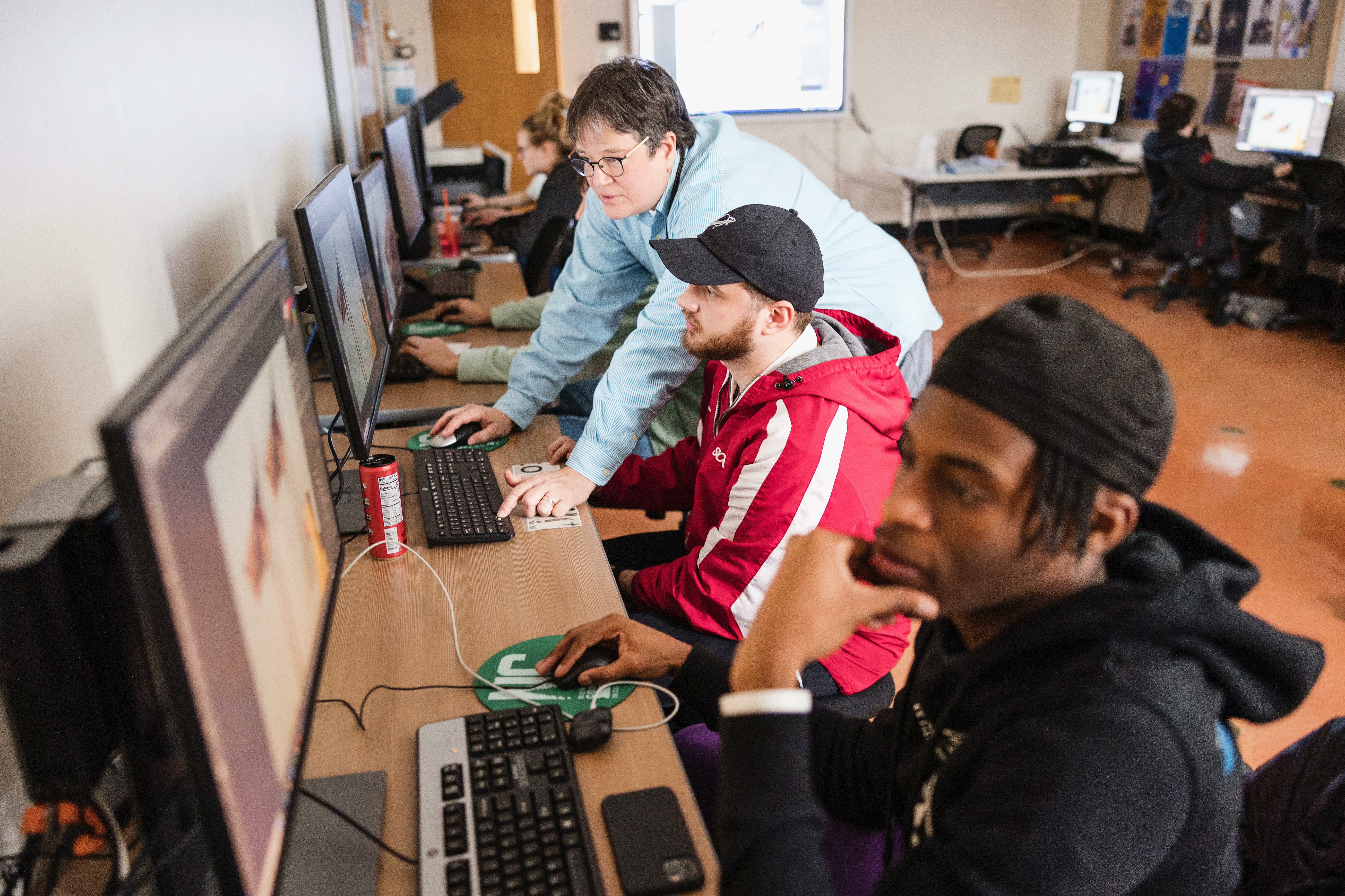 Students work at computers with a professor