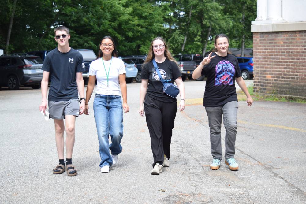A group of four students smile as they walk toward the camera while participating in a scavenger hunt 