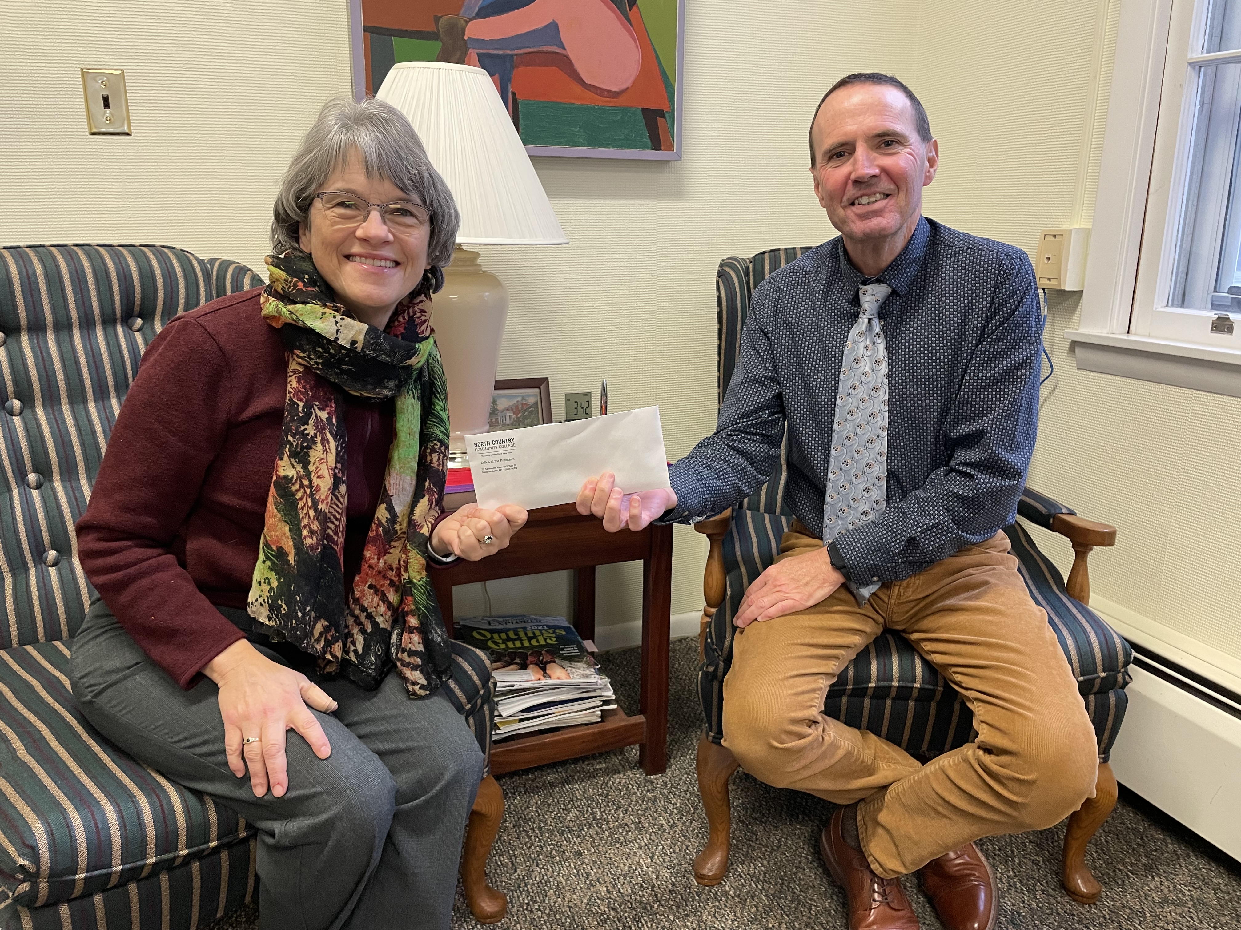 College President Joe Keegan hands off funds from a raffle to Homeward Bound board member Amy Tuthill