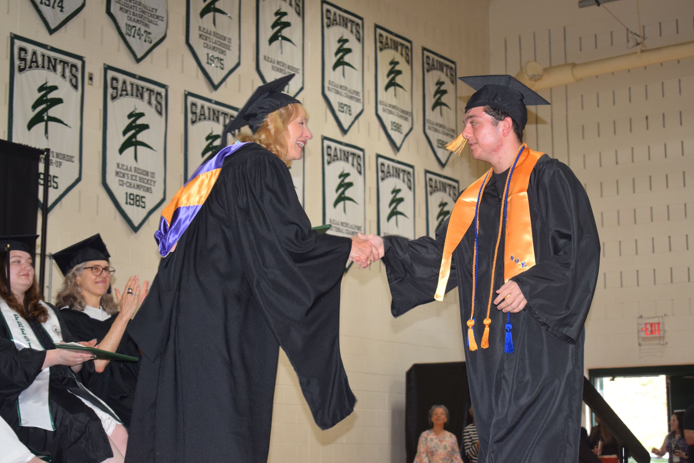 A student receives his degree on stage during a graduation ceremony