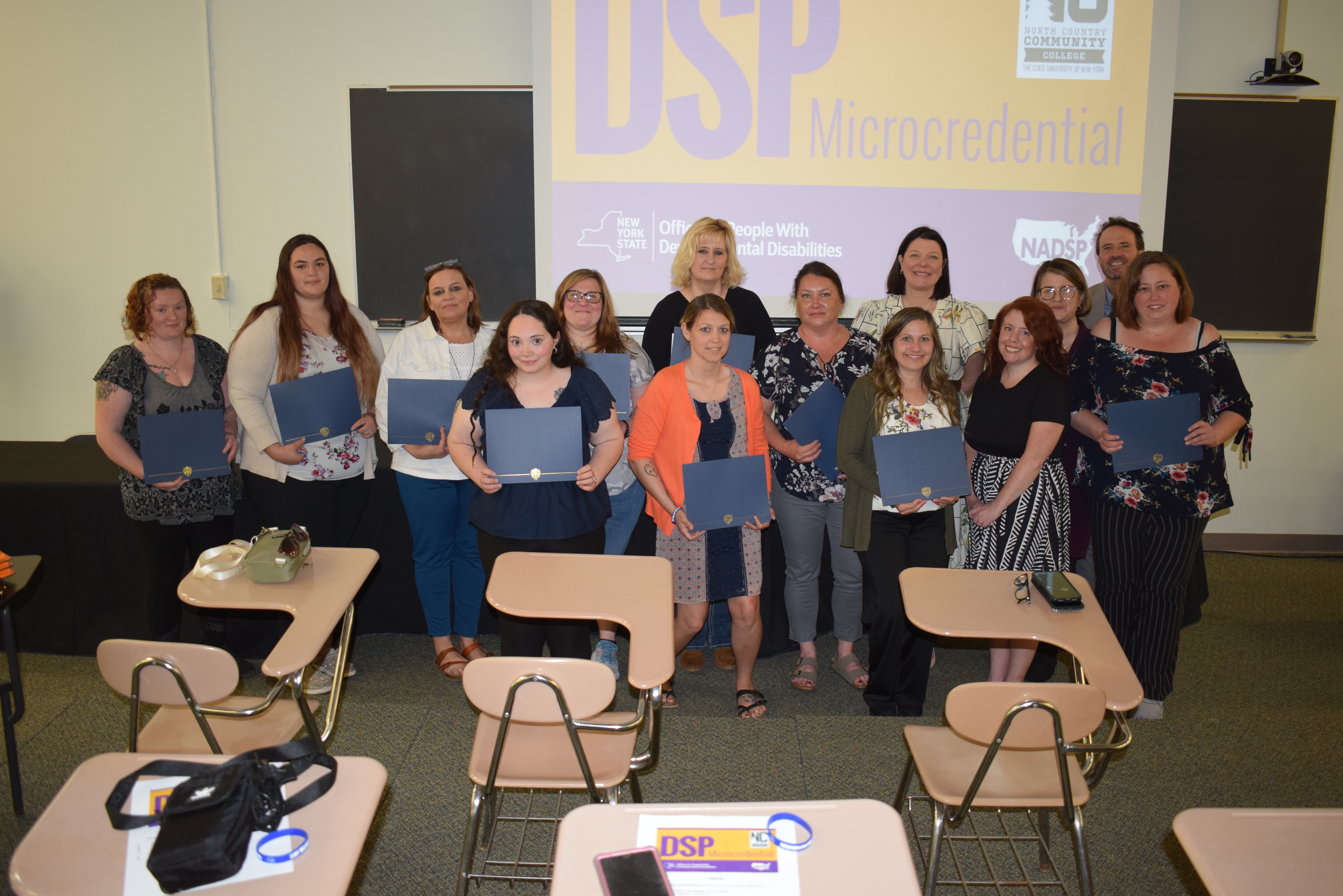 Students stand in a group holding their certificates