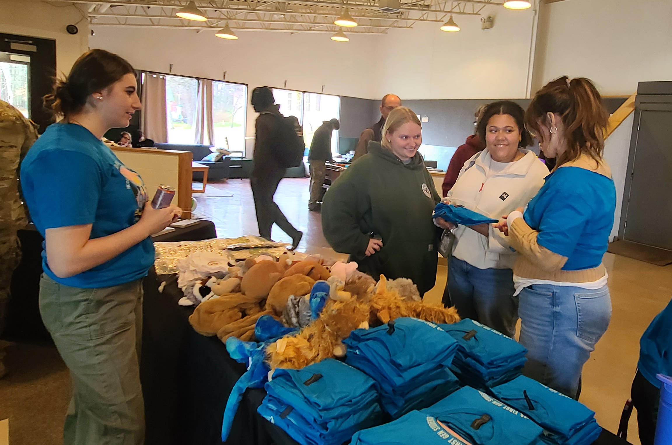 Students stand at a table with free items in a college lounge area