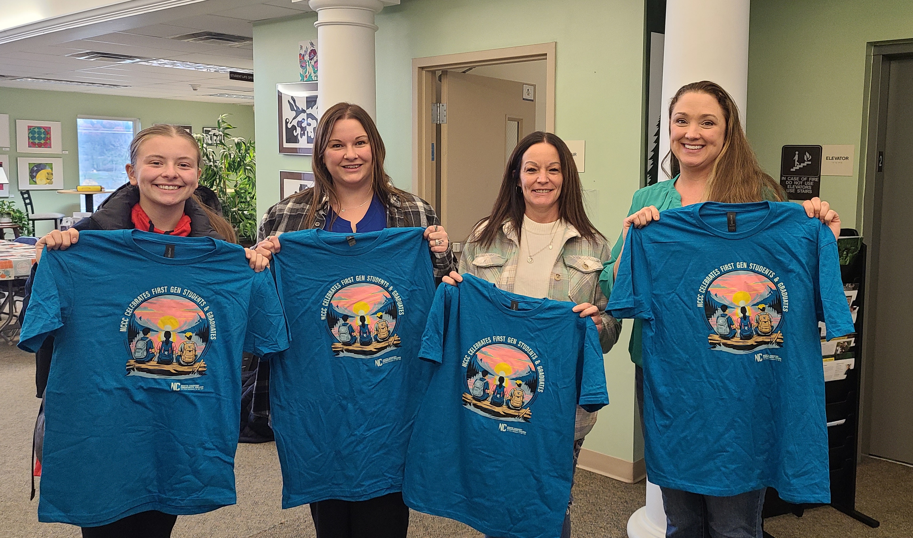 Students and staff stand and hold t-shirts