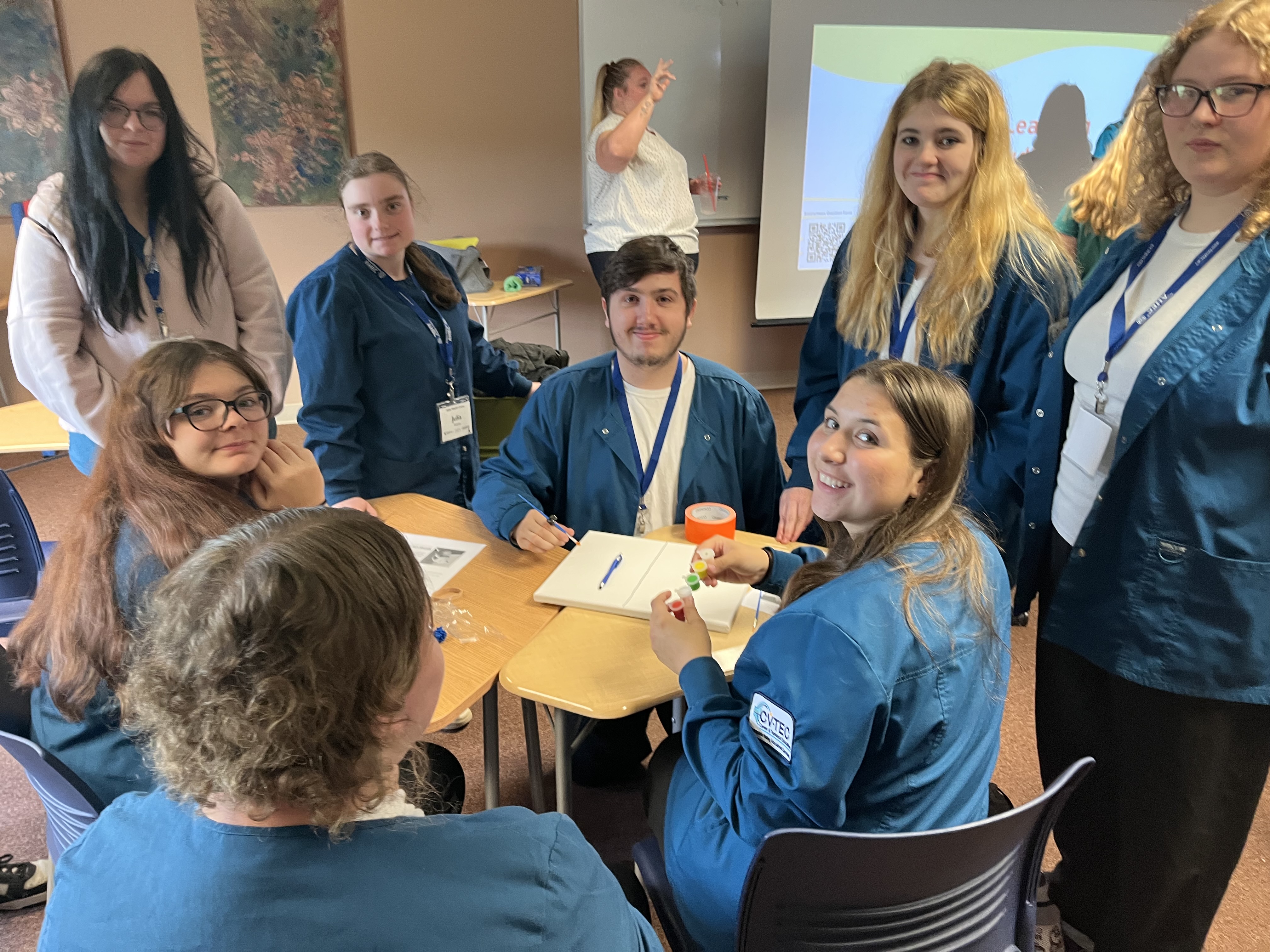 Students are gathered around a table during an activity at the Ticonderoga MASH Camp