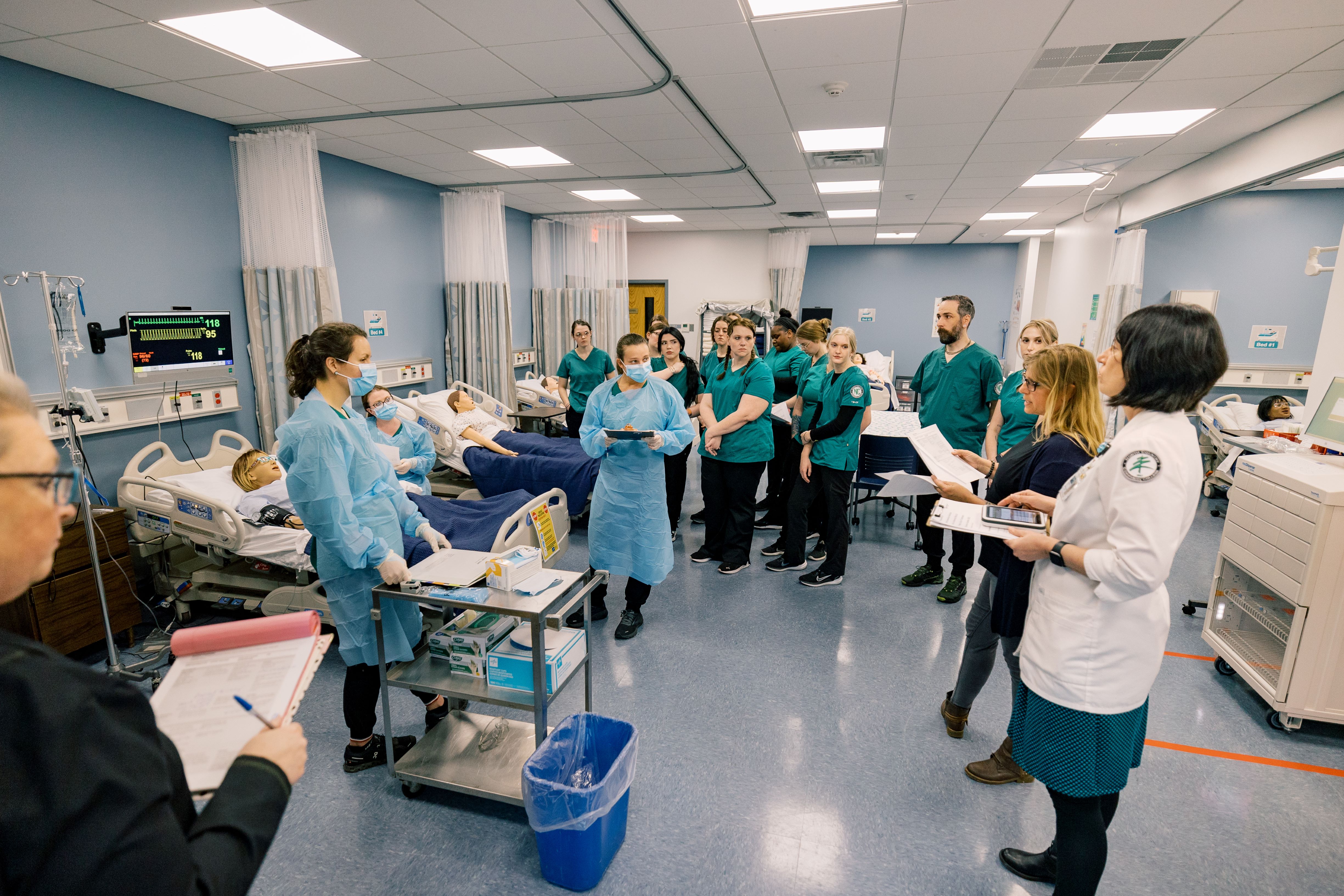 Students listen to instructors in a nursing classroom