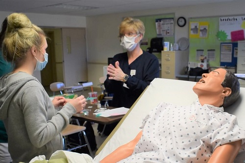 An instructor works with a student in the college's nursing program