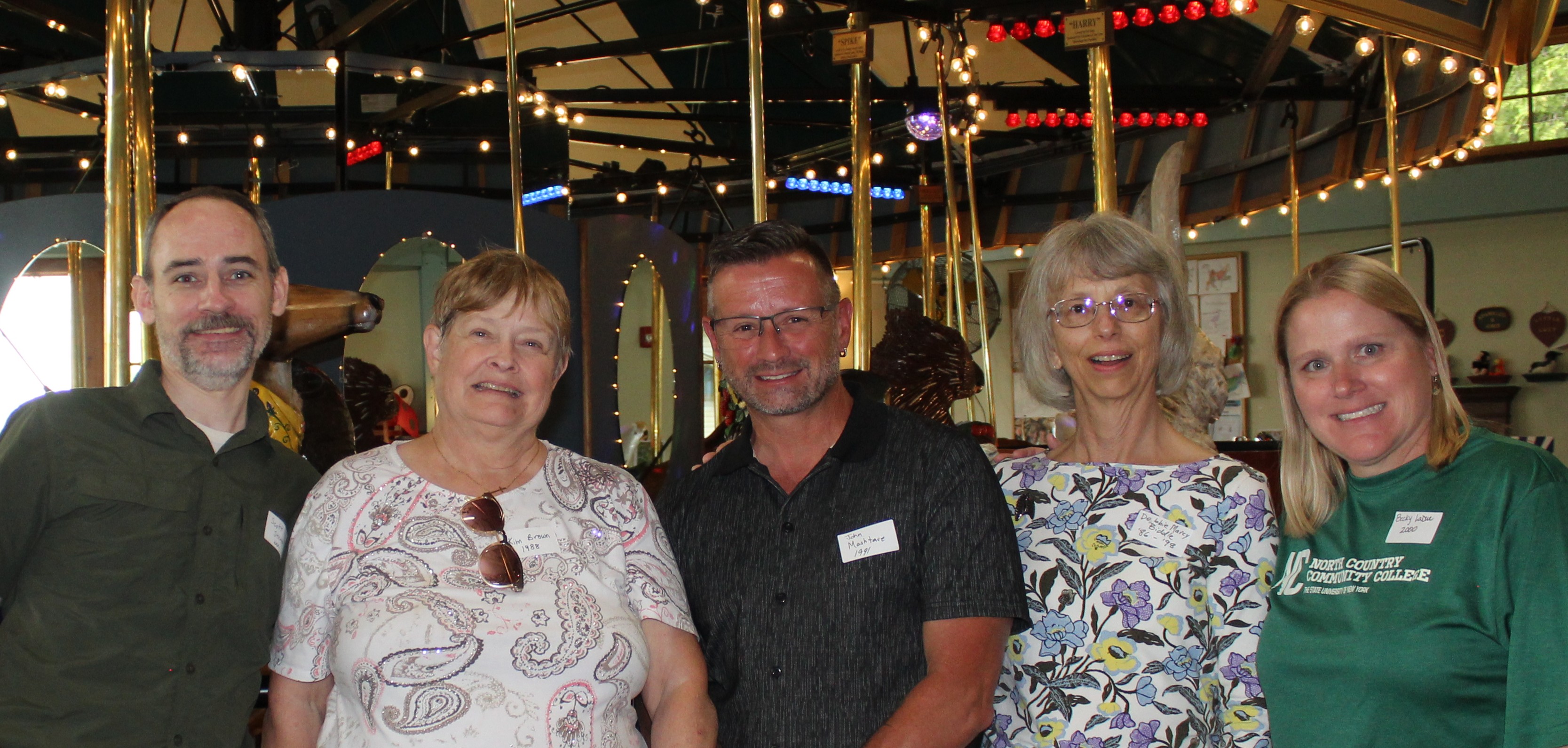 A group of five people pose for a picture at the Adirondack Carousel