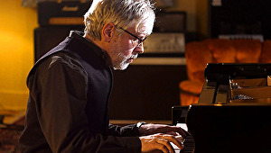 Adrian Carr sits as he plays piano